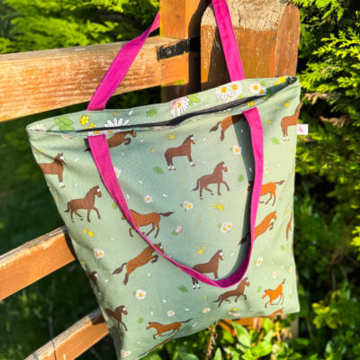 Bay horse patterned oversized tote bag with daisy print and pink straps hanging on a wooden gate