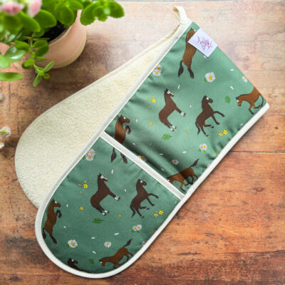 Full view of double oven gloves featuring bay horses and daisy pattern on green background