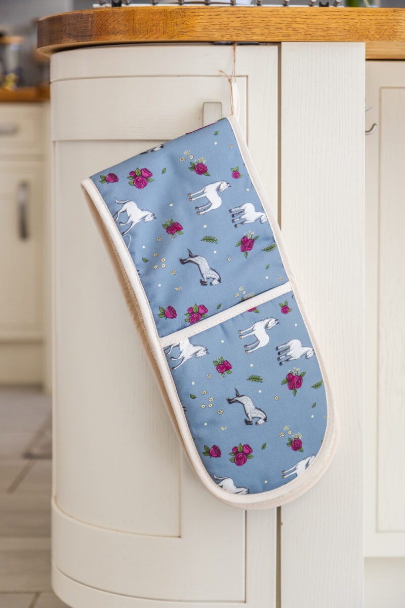 Grey horse and rose patterned double oven gloves hanging in a country kitchen.