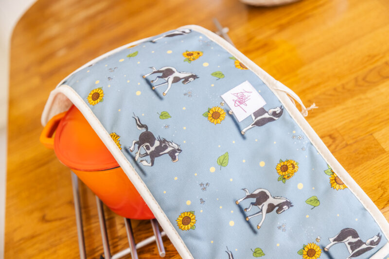 Close Up of double oven gloves with piebald horse and sunflower pattern on blue fabric