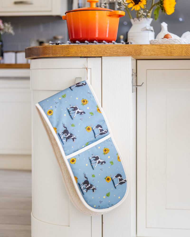 Full view of double oven gloves with piebald horse and sunflower pattern on blue fabric