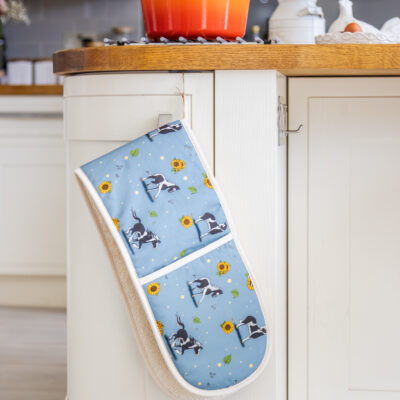 Full view of double oven gloves with piebald horse and sunflower pattern on blue fabric